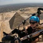 Happy woman paragliding with the Pyramids of Giza and Cairo skyline in the background.
