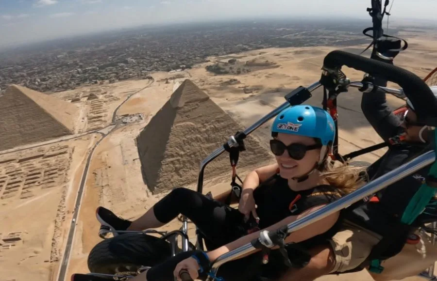 Happy woman paragliding with the Pyramids of Giza and Cairo skyline in the background.