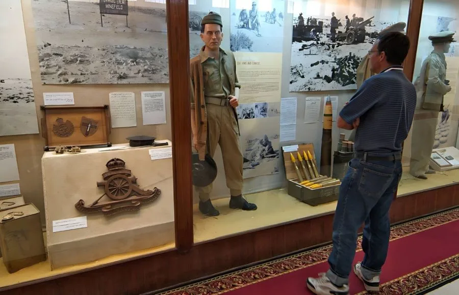 A tourist observes a World War II soldier mannequin and display of British artillery insignia and shells inside the El Alamein Military Museum.