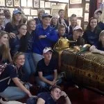 A group of tourists posing with a golden Egyptian sarcophagus replica at the Egypt Papyrus Institute.