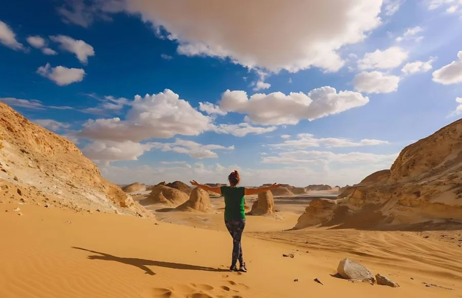 A tourist with arms wide open on a sand dune, enjoying the view in the White Desert Protected Area, Egypt.