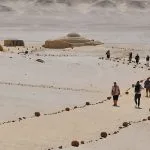 Visitors walking on a path marked by stones toward the desert museum buildings at Wadi El Hitan.