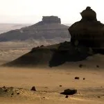 Dramatic rock formations stand tall in the desert landscape of Wadi Al-Hitan, Egypt.