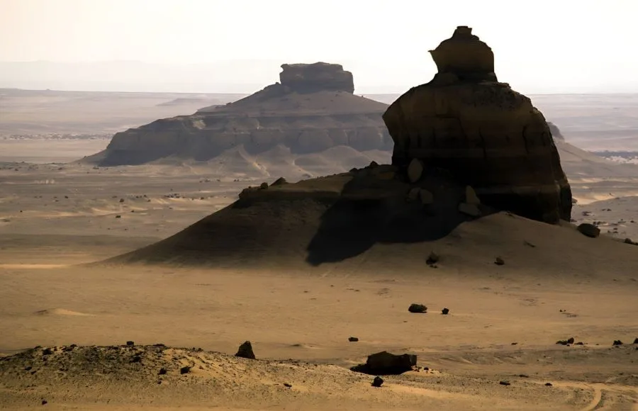 Dramatic rock formations stand tall in the desert landscape of Wadi Al-Hitan, Egypt.