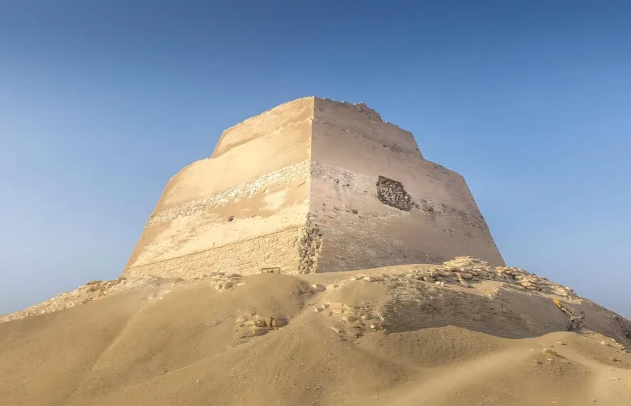 The ancient Meidum Pyramid in Egypt standing against a clear blue desert sky.