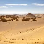 Wadi Al-Hitan trail winding through the Western Desert of Egypt's striking rock formations and golden sand dunes.