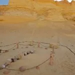 Partially excavated whale skeleton surrounded by a small fence in the sandy desert of Wadi El Hitan (Whale Valley).