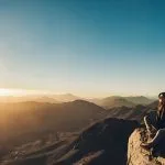 Woman-sits-on-edge-of-cliff-on-Mount-Sinai-and-looks-at-beautiful-sunrise