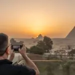 A-man-taking-a-photo-of-the-Pyramids-of-Giza-during-sunset-in-Egypt