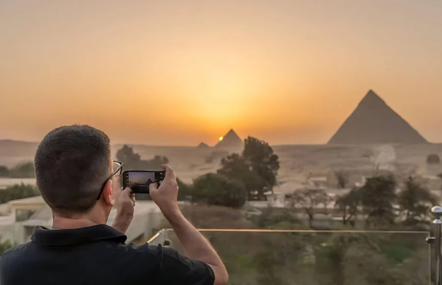 A-man-taking-a-photo-of-the-Pyramids-of-Giza-during-sunset-in-Egypt