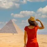 A-young-tourist-in-a-red-dress-looking-at-the-Pyramids-of-Giza