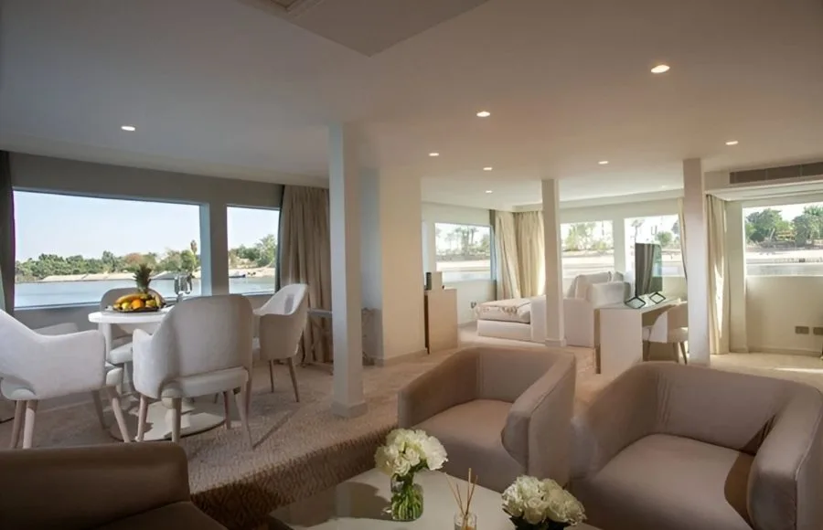 Interior view of the lounge area on the Kazazian Berge Dahabiya luxury yacht, featuring modern furnishings and large windows overlooking the Nile.
