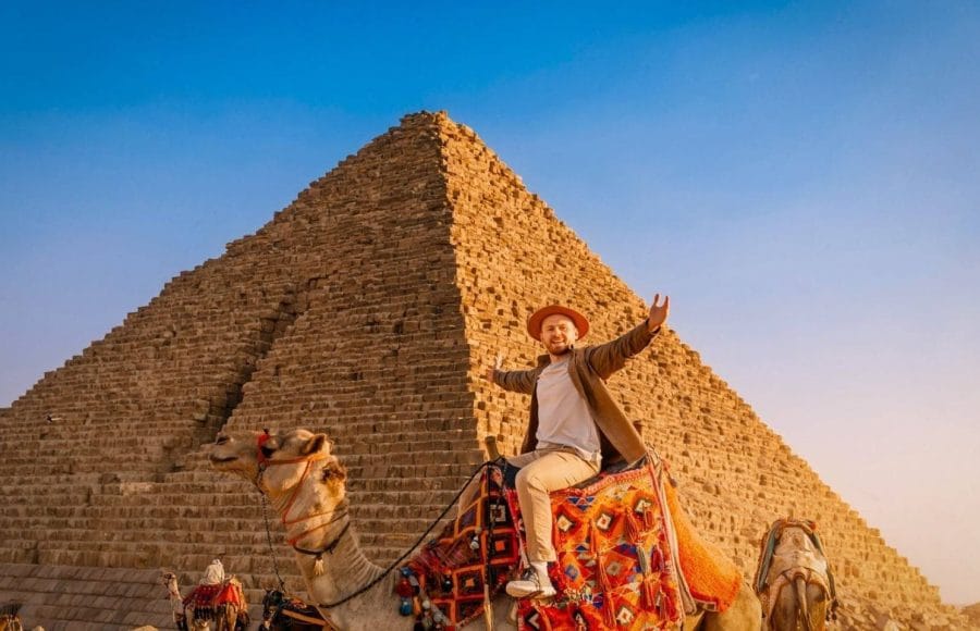 Tourist on a camel in front of the massive Great Giza Pyramid.