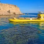 A semi-submarine tourist boat floating over clear water with coral reefs .