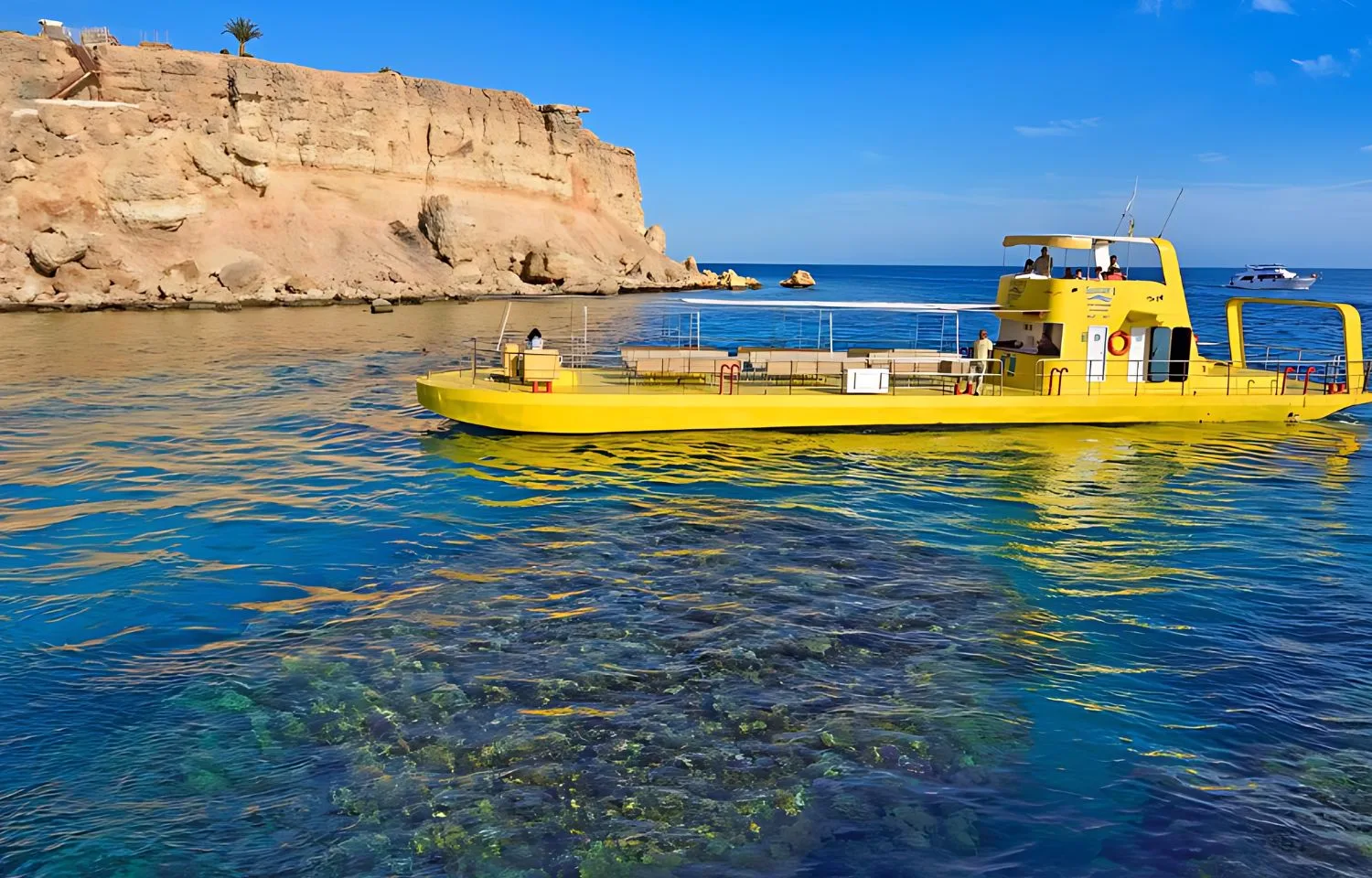 A semi-submarine tourist boat floating over clear water with coral reefs .