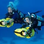 Divers-With-Diver-Propulsion-Vehicles-Exploring-A-Coral-Reef-Soma-Bay