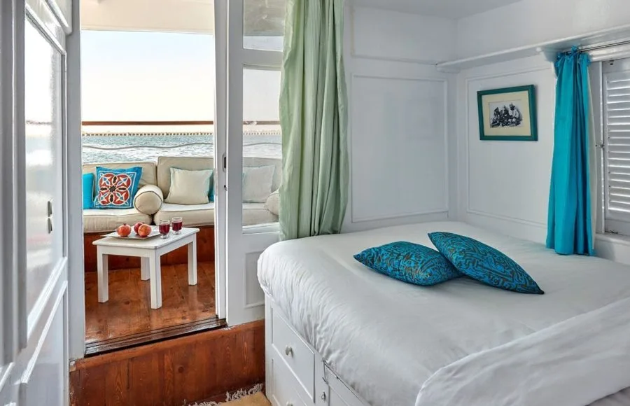 A view inside a cabin on the Lazuli Gordon Pacha Dahabiya Nile Cruise with a bed and a view outside.