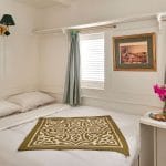 Cabin interior aboard the Lazuli Gordon Pacha Dahabiya Nile Cruise with a bed, two windows, and a small table.