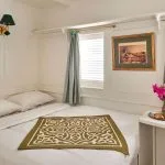 Cabin interior aboard the Lazuli Gordon Pacha Dahabiya Nile Cruise with a bed, two windows, and a small table.