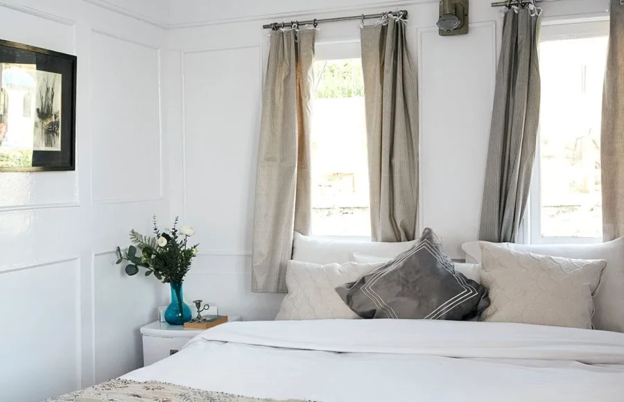 A bright, elegantly decorated living room suite on a Nile cruise boat with white sofas, blue cushions, and small iron side tables.