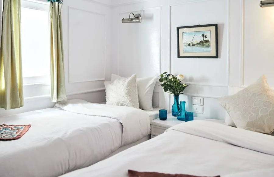 A twin cabin on the Lazuli Roi Farouk Dahabiya Nile Cruise with two single beds and Nile views.