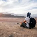 Traveler-Sits-And-Looks-At-Sinai-Desert-And-Mountains-At-Sunset