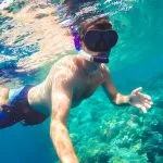 Underwater-with-snorkeling-man-fish-and-coral-reef-Safaga