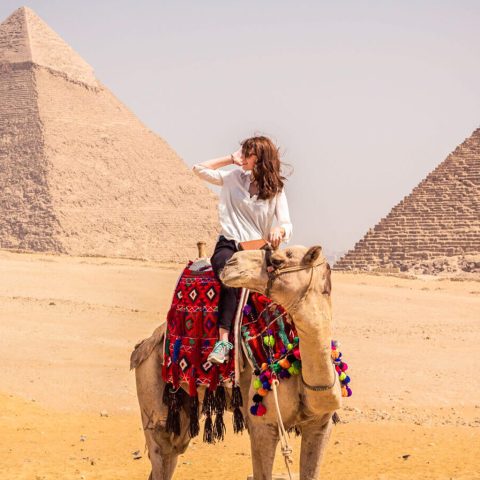A tourist riding a camel in front of the Giza Pyramids, representing popular 3-day Egypt tour packages.