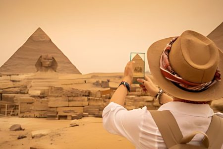 Tourist Wearing A Sun Hat Photographs The Sphinx And The Great Pyramids Of Giza During An Exciting 3 Day Tour In Cairo.