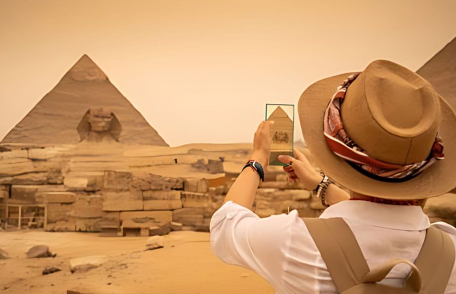 Tourist wearing a sun hat photographs the Sphinx and the Great Pyramids of Giza during an exciting 3 Day Tour in Cairo.