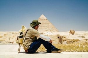 Tourist sitting and admiring the Great Pyramid of Giza and the Sphinx in the desert landscape, a key attraction for a 3 day Egypt itinerary.