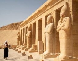 Traveler standing before the multi tiered Mortuary Temple of Hatshepsut at Deir El Bahari, Luxor, Egypt, with towering pharaonic statues, a key stop on a 3 day Egypt itinerary.