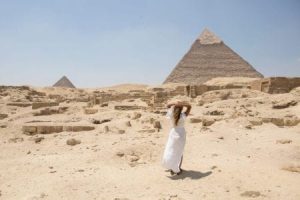 Women in traditional white attire walking towards the Giza Pyramids, ideal for a 4 days in Egypt itinerary.