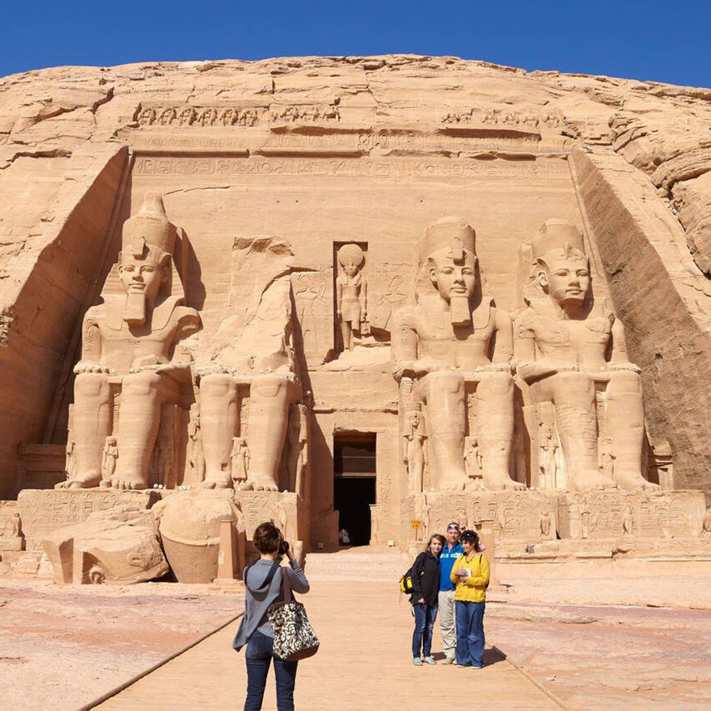 A group of tourists photographing the massive, rock-cut facade of the Abu Simbel temple during their 9 day Egypt tour packages.