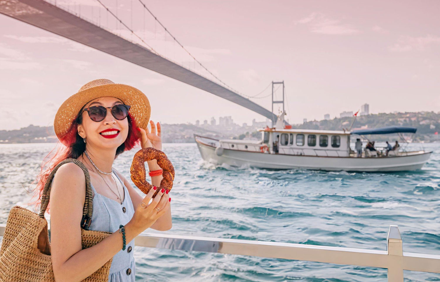 A Tourist enjoys a fresh simit by the Bosphorus in Istanbul savoring the traditional sesame covered snack on a summer day