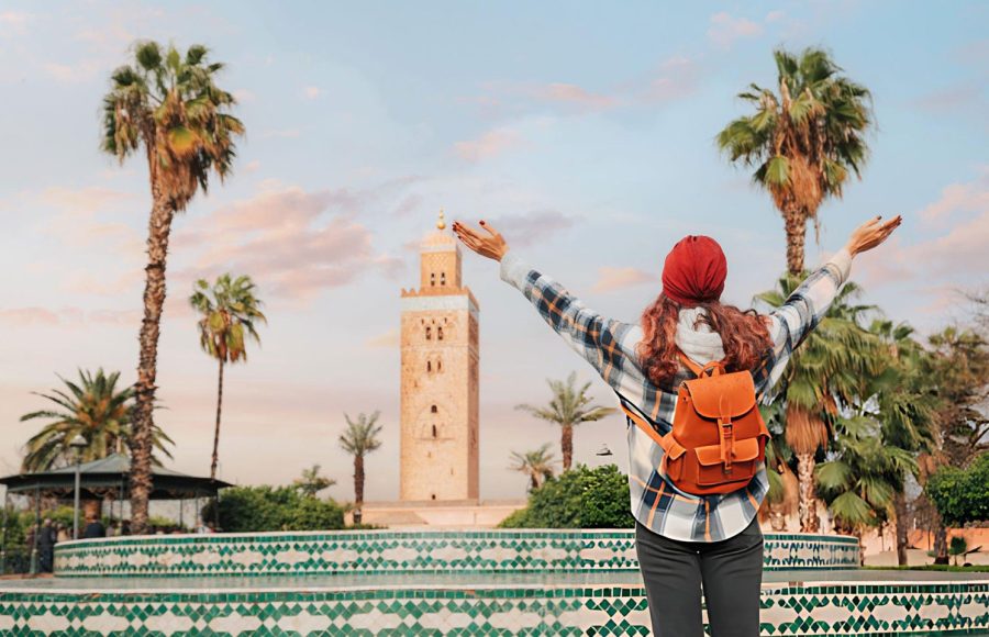 A-Young-woman-celebrating-reaching-Koutoubia-Mosque-in-Marrakech-with-open-arms-enjoying-her-trip-to-Morocco