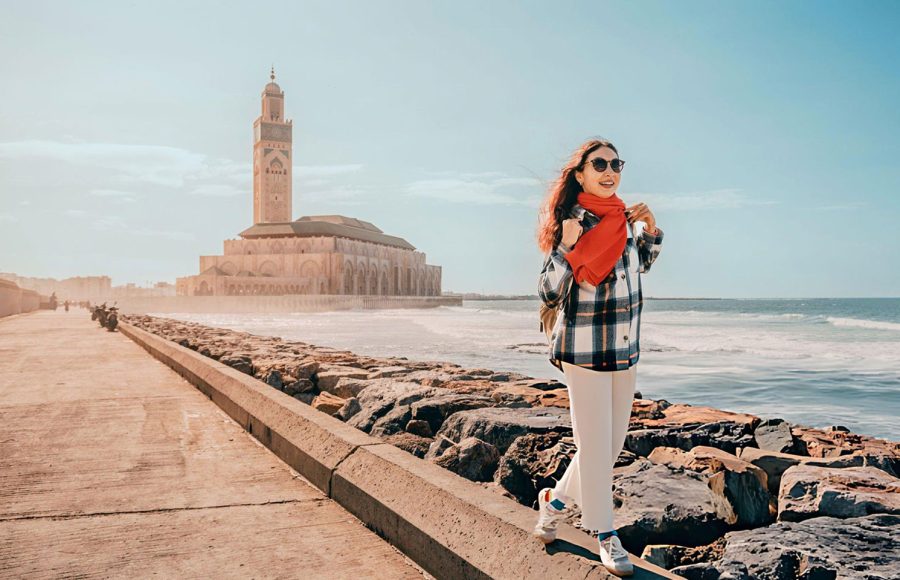 A-Young-woman-walking-on-the-breakwater-near-Hassan-II-Mosque-in-Casablanca-Morocco-during-a-sunny-day