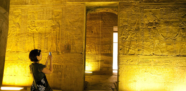 A female tourists photographing hieroglyphics and relief carvings inside the Temple of Horus at Edfu Upper Egypt