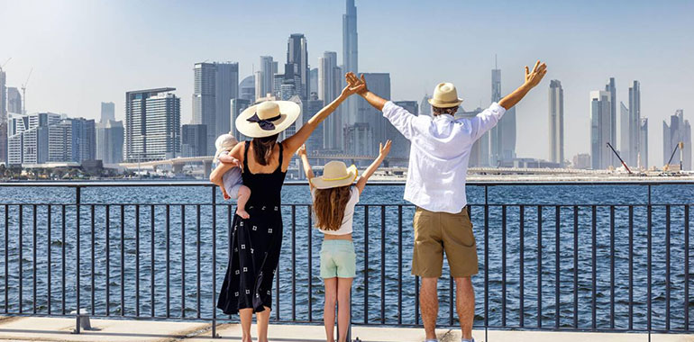 A Happy Tourist Family Of Four Looks At The Urban Skyline Of Dubai Uae During Their City Vacations