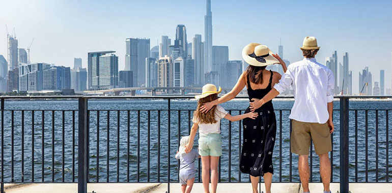 A Tourist Family Of Four Looks Together At The Urban Skyline Of Dubai Uae During Their Vacations