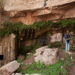 A-tourist-looking-at-a-Nabatean-rock-cut-aqueduct-in-Ain-Shalaaleh-also-known-as-Lawrence’s-Spring-located-in-Wadi-Rum-desert
