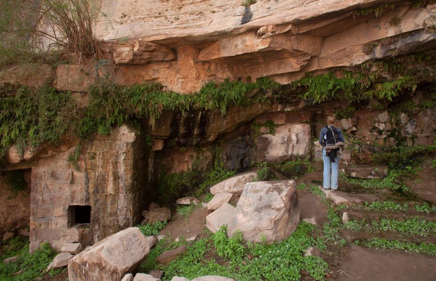 A-tourist-looking-at-a-Nabatean-rock-cut-aqueduct-in-Ain-Shalaaleh-also-known-as-Lawrence’s-Spring-located-in-Wadi-Rum-desert