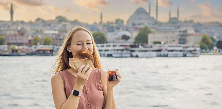 A woman in Istanbul having breakfast with Simit and a glass of Turkish tea
