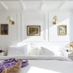 A bright, elegant white cabin on a Nile cruise ship featuring a large bed with a view of the river.