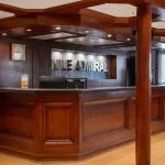 The elegant, dark wood reception desk of the Nile Admiral cruise ship lobby with the ship's name prominently displayed on the back wall.