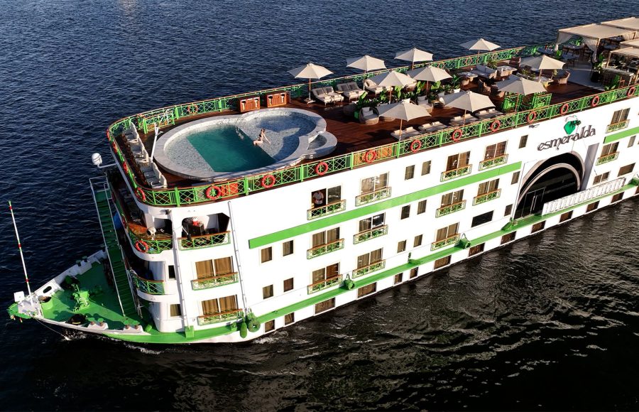 Aerial view of the MS Esmeralda Nile Cruise sailing on the river, showcasing its top sun deck, swimming pool, and multi-level guest cabins.