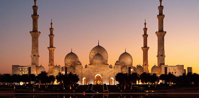 Aerial view of the majestic Sheikh Zayed Mosque reflecting in the still waters at sunset Abu Dhabi United Arab Emirates