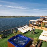 Couple walking on a green turf sundeck with a blue jacuzzi.