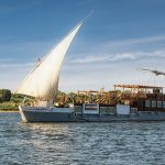 Agatha Christie Dahabiya sailing on the Nile River with full sails.