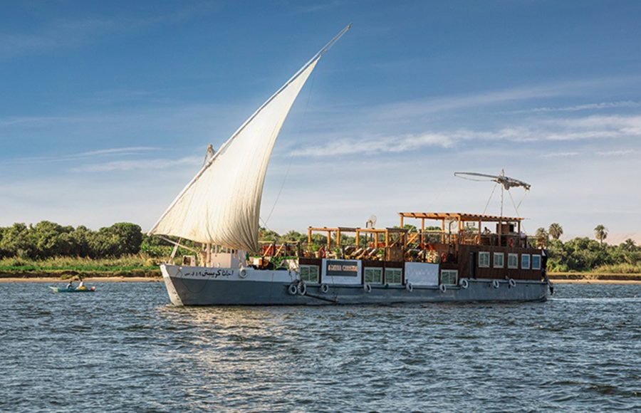 Agatha Christie Dahabiya sailing on the Nile River with full sails.